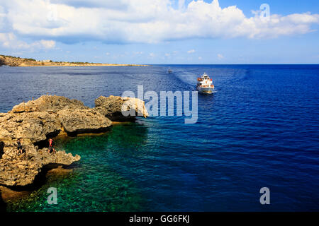 tourist cruise ship coming in to shallow water and caves at Cape Greko, Cyprus. Stock Photo