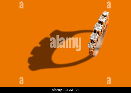 Diamond ring with shadow over an orange background Stock Photo