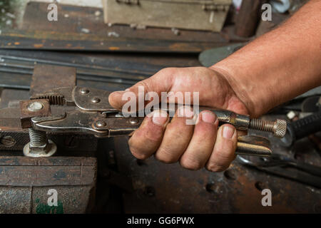 dirty hands of a worker who makes strength on a screw with a clamp Stock Photo