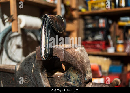 wallet with lots of money clamped in a vise in an old workshop Stock Photo