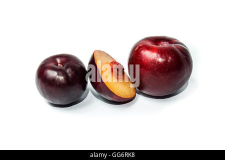 two red whole plums and half on white background Stock Photo