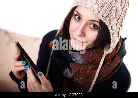 Girl holding smartphone with a empty blank screen monitor and a cup of coffee or tea on the background in a home atmosphere, hipster using in hands a smart phone with space for information, blur Stock Photo