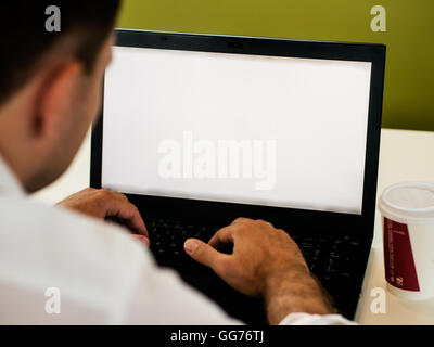 Man using laptop with blank screen on desk Stock Photo