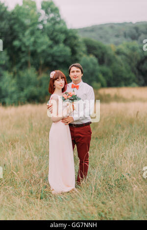 Young wedding couple enjoying romantic moments outside standing on a summer meadow Stock Photo