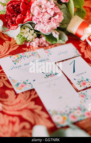 Composition flowers and invitations with envelopes on red background Stock Photo