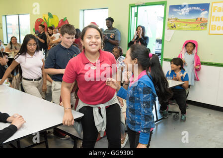 Multi-ethnic group of junior high students congregate in school cafeteria during after-school Earth Day program Stock Photo