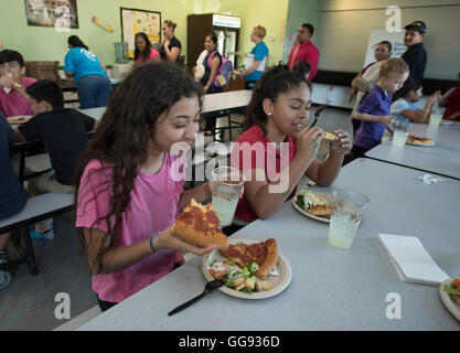 Girls eat pizza in cafeteria during after-school activity at middle school in Austin, Texas Stock Photo