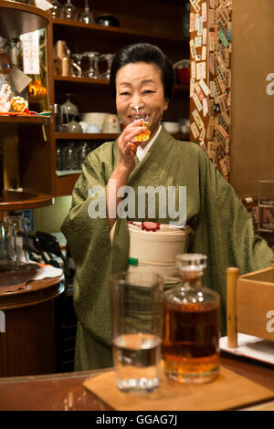 Senior Japanese woman in kimono drinking sake Stock Photo