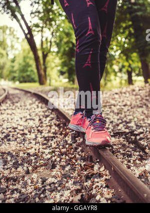 A girl in sneakers, balancing on rail. Stock Photo