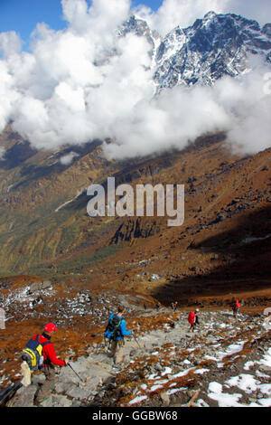 View  of trekkers and Sherpa on decent of Zatrwa La Pass with mist over mountains Stock Photo