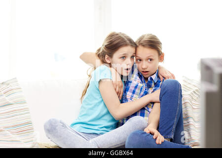 scared little girls watching horror on tv at home Stock Photo