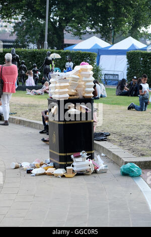 A street side public rubbish bin full to capacity and overflowing with fast food containers Stock Photo