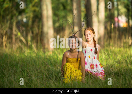 Two little cute girls posing in a pine forest. Stock Photo