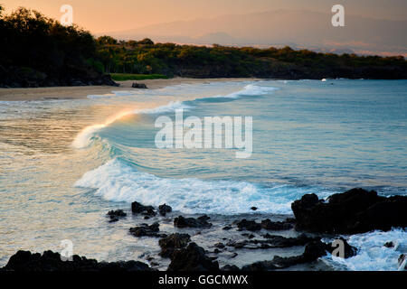 Waves and sunrise on Hapuna Beach with Hualalai volcano in background. Hawaii Island Stock Photo