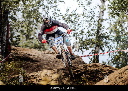 male athlete competitor downhill rides in forest during National championship downhill Stock Photo