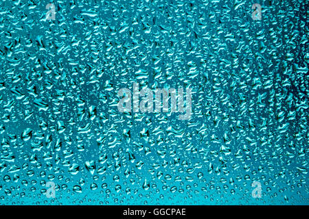 Raindrops on a glass surface in turquoise color as a background Stock Photo