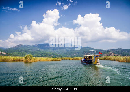 TURKEY, DALYAN, MUGLA - JULY 19, 2016 Pleasure boat with tourists in the mouth of the Dalyan River under Lycian tombs Stock Photo