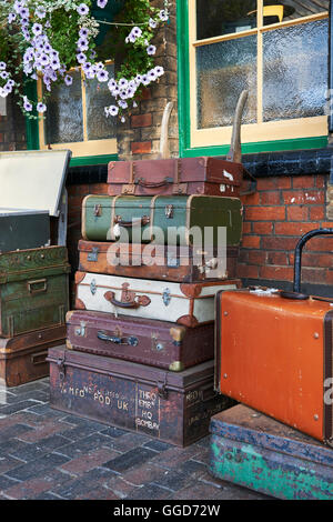 Old suitcases at a steam railway station stacked on a barrow cart, on the platform Stock Photo