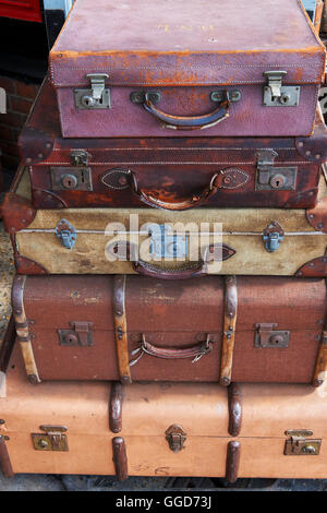 Old suitcases at a steam railway station stacked on a barrow cart, on the platform Stock Photo