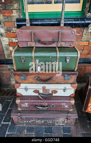 Old suitcases at a steam railway station stacked on a barrow cart, on the platform Stock Photo