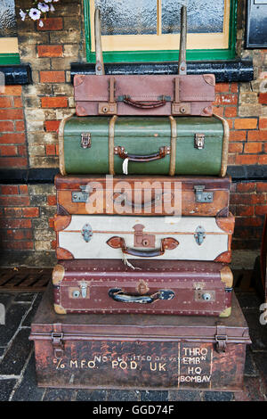 Old suitcases at a steam railway station stacked on a barrow cart, on the platform Stock Photo