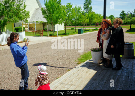 A woman taking a photo of tourists by the statue of Anne of Green Gables in Avonlea Village, Cavendish, prince Edward Island Stock Photo