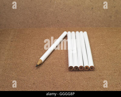 six pencils with one pencil sharpened and five pencils unsharpened on wooden board Stock Photo