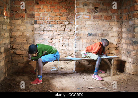 Two african school children in a rural school in Uganda/Rwanda take a school test, sitting opposite each other on wooden benches Stock Photo