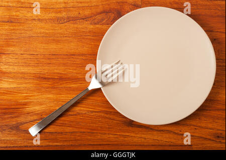 empty plate and fork on wooden table Stock Photo