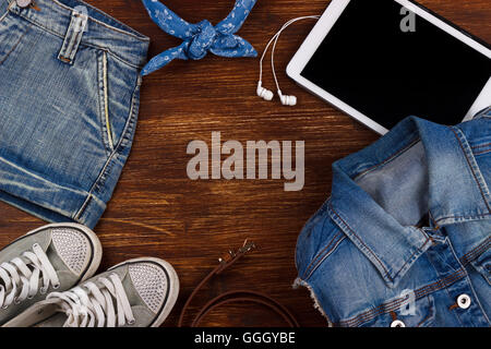 Tablet, earphones,denim clothing and sneakers on the wooden background Stock Photo