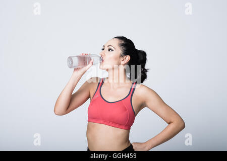Woman in her 20s in fitness gear drinking water Stock Photo