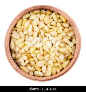 Shelled pine nuts in a bowl on white background. Edible seeds of Korean pines family Pinaceae, genus Pinus, in a wooden bowl. Stock Photo