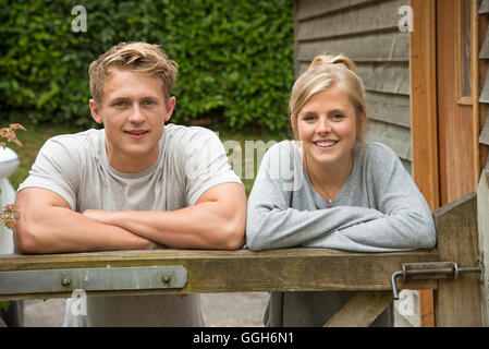 Portrait of a teenage couple leaning on a garden gate Stock Photo