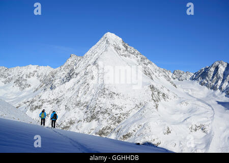 Two female back-country skiers downhill skiing from Kuhscheibe, Schrankogel in background, Kuhscheibe, Stubai Alps, Tyrol, Austr Stock Photo