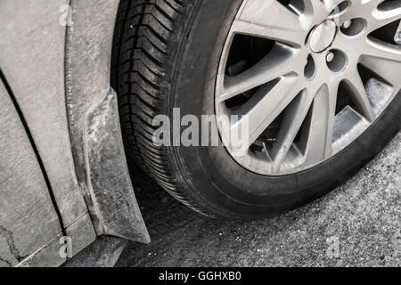 Dirty unidentifiable car wheel with light alloy disc on country road, close up photo Stock Photo