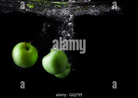 Three green apples splashing into water on black background. Copy space. fruits Stock Photo