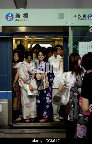 Crowded subway train with two laughing modern geisha girls at Shinbashi Station, Tokyo, Kanto Region, Honshu, Japan Stock Photo