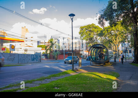 CURITIBA ,BRAZIL - MAY 12, 2016: passengers waiting for the bus on the station while some cars are driving in the street Stock Photo