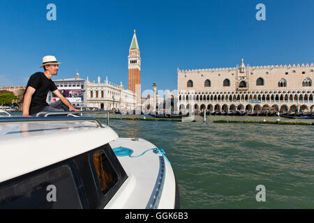 Young man with hat enjoing his view from the top of this boat towards the Campanile and Piazza San Marco, Venice, Italy, Europe Stock Photo