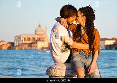 Young couple kissing on the banks of the Canale della Giudecca in Dorsoduro with Chiesa del Redentore church in the distance, Ve Stock Photo