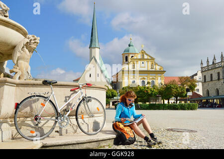 Cyclist resting at Marienbrunnen fountain, Kapellplatz, Altoetting, Upper Bavaria, Germany Stock Photo