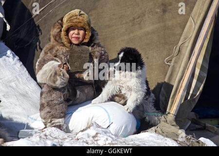 nomad child dressed in reindeer skins with a young dog, Chukotka Autonomous Okrug, Siberia, Russia Stock Photo