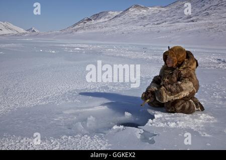 Reindeer nomad boy dressed in reindeer skins ice fishing, Chukotka Autonomous Okrug, Siberia, Russia Stock Photo