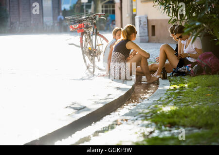 Teenage girls cooling their feet in a stream, Freiburg im Breisgau, Black Forest, Baden-Wuerttemberg, Germany Stock Photo