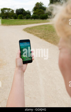 Ostfildern, Germany - July 17, 2016: A woman is playing the augmented reality smartphone app 'Pokemon GO' on her Apple iPhone wh Stock Photo