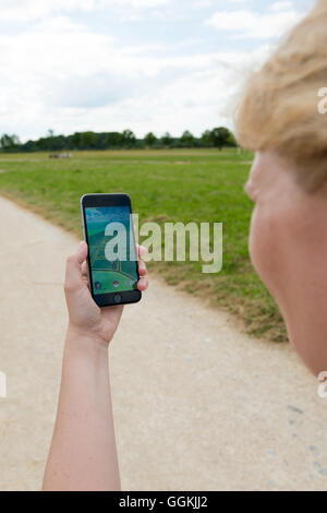 Ostfildern, Germany - July 17, 2016: A woman is playing the augmented reality smartphone app 'Pokemon GO' on her Apple iPhone wh Stock Photo