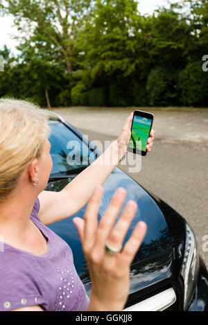 Ostfildern, Germany - July 17, 2016: A woman playing Pokemon Go on her smartphone is hit by a car while carelessly crossing the Stock Photo