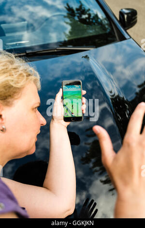 Ostfildern, Germany - July 17, 2016: A woman playing Pokemon Go on her smartphone is hit by a car while carelessly crossing the Stock Photo