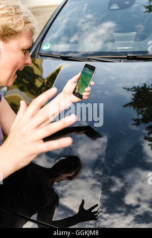 Ostfildern, Germany - July 17, 2016: A woman playing Pokemon Go on her smartphone is hit by a car while carelessly crossing the Stock Photo