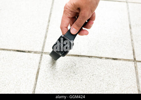 Ostfildern, Germany - July 31, 2016: A middle aged woman (only the hand is visible) is picking up a broken Apple Watch after it Stock Photo